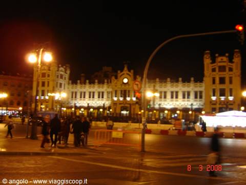 Valencia's Plaza del Ayuntamiento at night, illuminated facade with pedestrians crossing