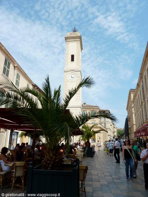 Clock tower above cafes and palm trees in Place de l'Horloge, Avignon