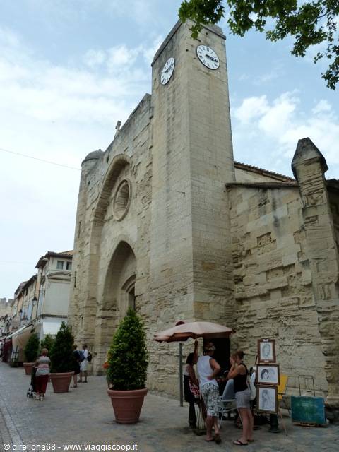 Tourists under an umbrella by the fortified stone church with clock tower