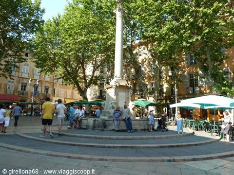 Tourists around a column fountain in a tree-lined square in Aix-en-Provence