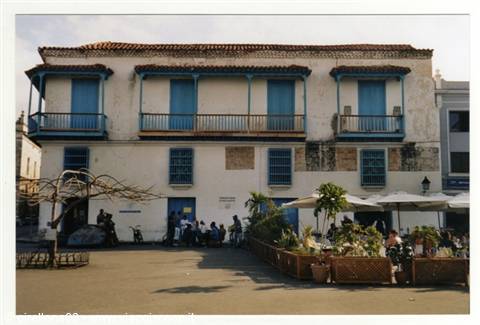 Colonial wooden balconies on white facade, planters and cafe umbrellas, Cartagena