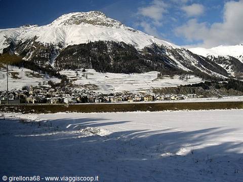 Snowy alpine village at the foot of mountains, snow-covered fields, Livigno