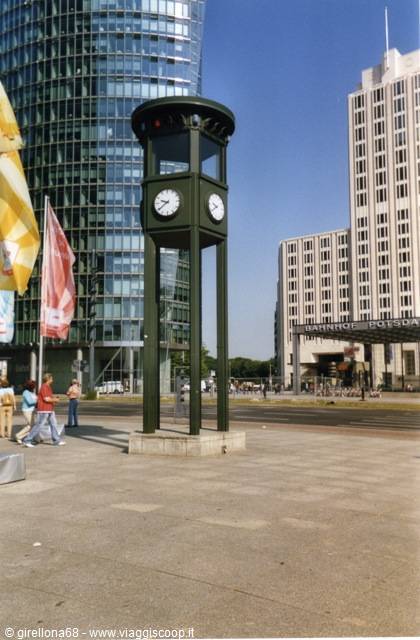 Green clock tower at Potsdamer Platz, Berlin, with skyscrapers and flags