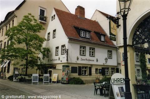 Trattoria in white house with red roof, sidewalk tables, wrought-iron lantern