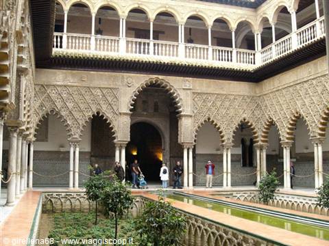 Tourists in the Mudéjar courtyard of Seville's Alcázar, carved arches and central pool