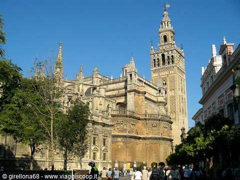 The Giralda and Seville Cathedral in sunlight, with tourists on the street
