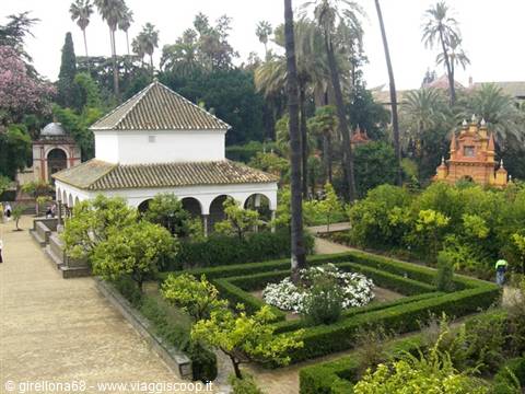 Arched pavilion with green-tiled roof amid hedges in Seville's Alcázar gardens