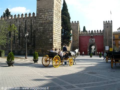 Yellow carriage in front of the crenellated walls of Seville's Alcázar