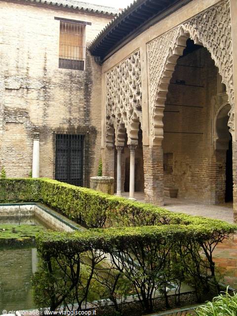 Moorish stucco arches over the courtyard pond at Seville's Alcázar