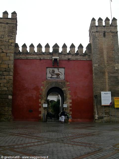 Red crenellated gate with lion emblem at the Alcázar of Seville