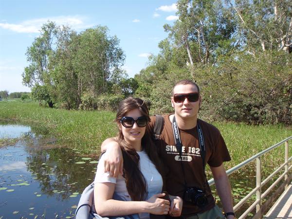 Couple with camera on a wooden boardwalk over a wetland with water lilies