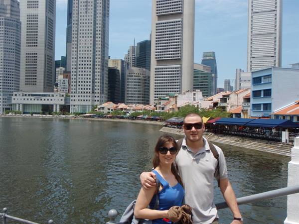 Couple in sunglasses on the bridge at Boat Quay, Singapore, skyscrapers by the river