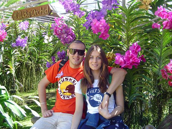 Couple sitting among pink and purple orchids at Bai Orchid farm