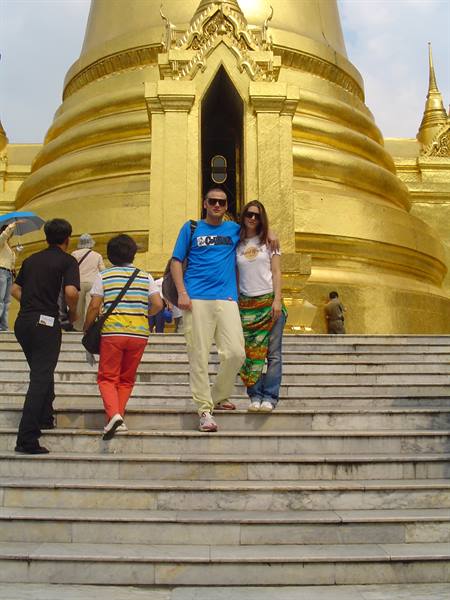 Tourist couple on marble steps in front of the golden stupa of Wat Phra Kaew