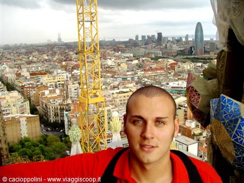 Young man in red on the Sagrada Familia tower, Barcelona skyline under gray clouds