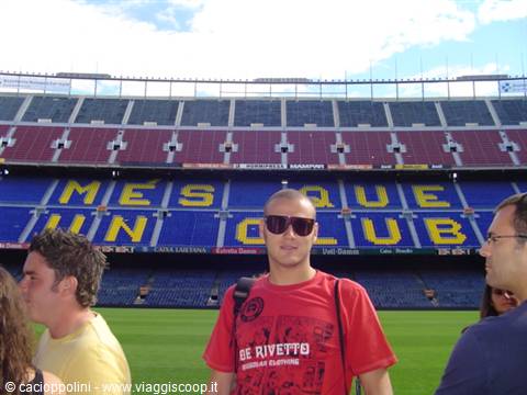 Tourist in sunglasses at Camp Nou stadium, below the Més que un club sign
