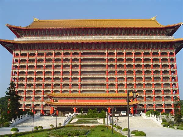 Red facade of Taipei Grand Hotel with golden roof and garden