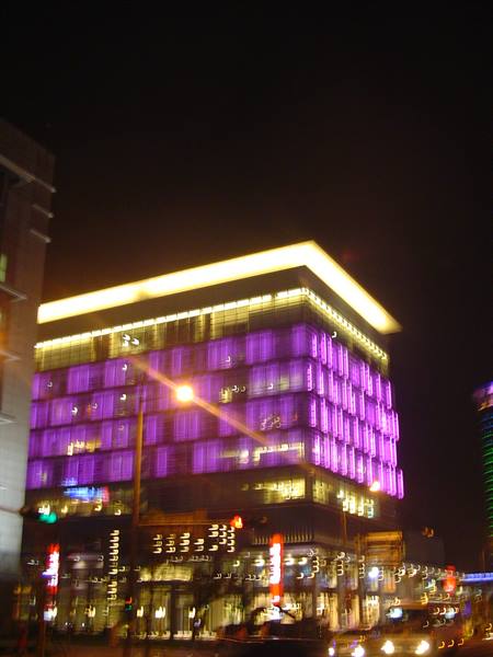 Night building lit in purple, blurred shot with smeared street lights