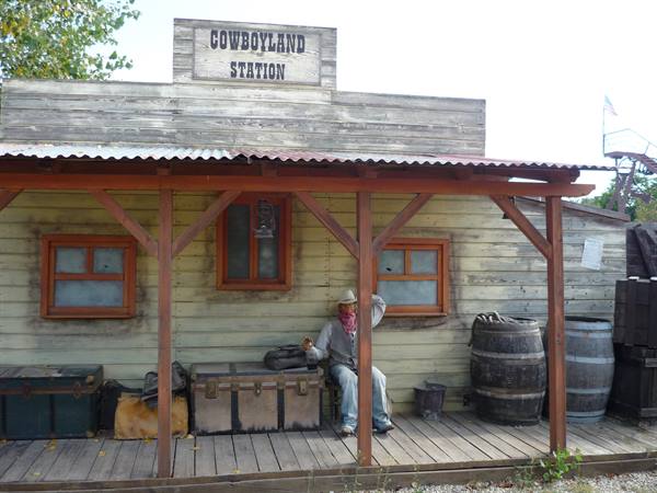 Man in hat sitting on the wooden porch of Cowboyland Station