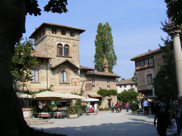Visitors stroll past medieval brick houses and a tower at Turin's Valentino medieval village