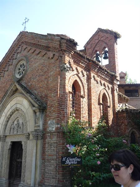 Small brick church with bell tower and rose window, Secret Garden sign