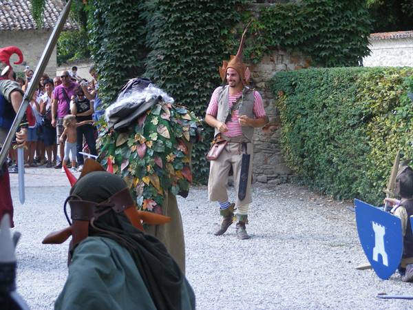 Performers in elf and goblin costumes entertain visitors in a gravel courtyard