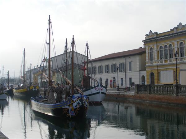Historic sailing boats moored along the canal harbor of Cesenatico