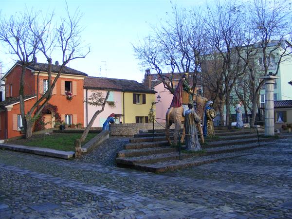 Life-size nativity statues on stone steps, cobbled square and pastel houses