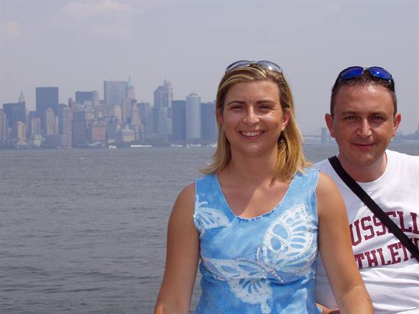 Smiling couple in foreground, Manhattan skyline across the hazy water