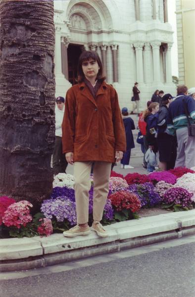 Woman in brown jacket beside hydrangeas in front of Sacré-Cœur, Montmartre
