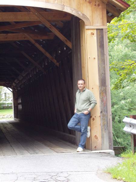 Man leaning on wooden pillar of a covered bridge