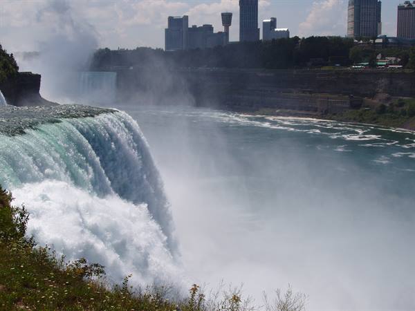 Niagara Falls, water plunging with mist and skyscrapers on the far shore