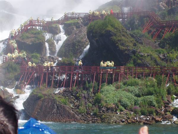 Red wooden walkways with tourists in yellow raincoats at Niagara Falls