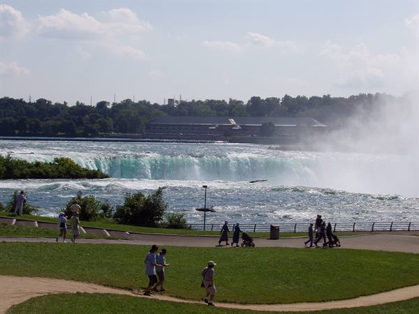 Tourists strolling on the lawn in front of Niagara Falls
