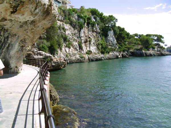 Walkway with iron railing along white cliffs and turquoise water