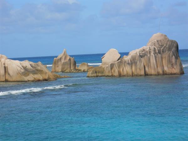 Granite rocks in turquoise water, white waves, cloudy sky