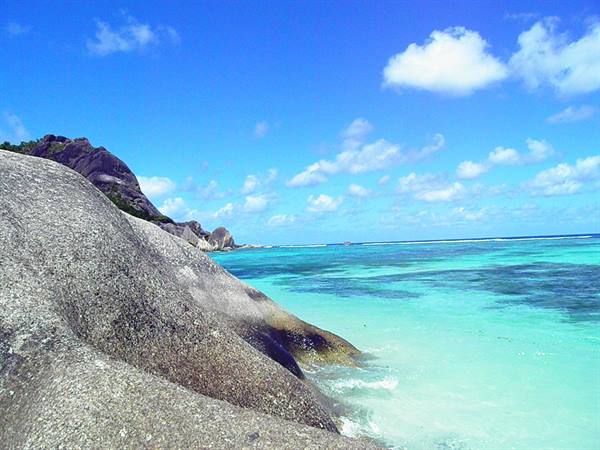 Large granite boulders meet turquoise waves on a sunny tropical beach