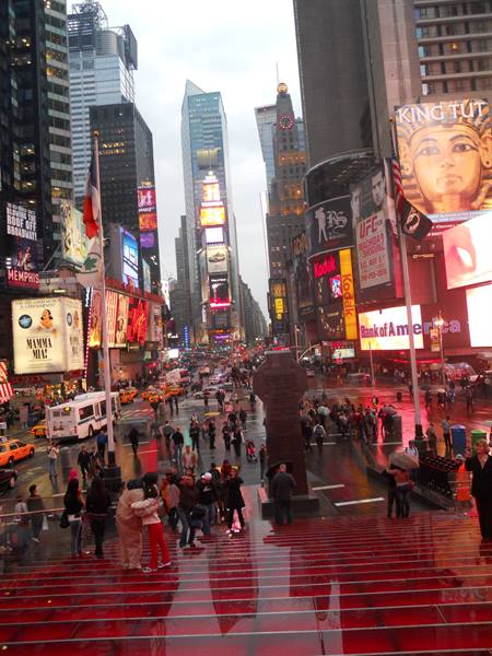 Crowd under glowing billboards in Times Square, New York, after rain