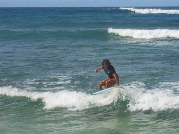 Surfer on blue board rides a wave through white foam and green sea