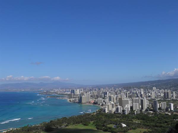Waikiki high-rises along turquoise bay, blue sky, tropical greenery in foreground