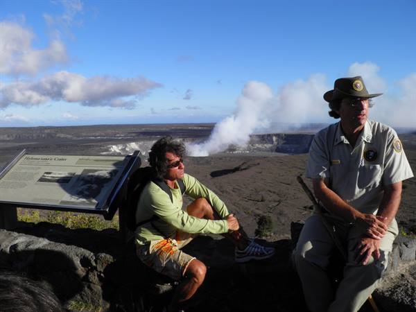 Tourist and ranger by an information sign at steaming Halema'uma'u crater
