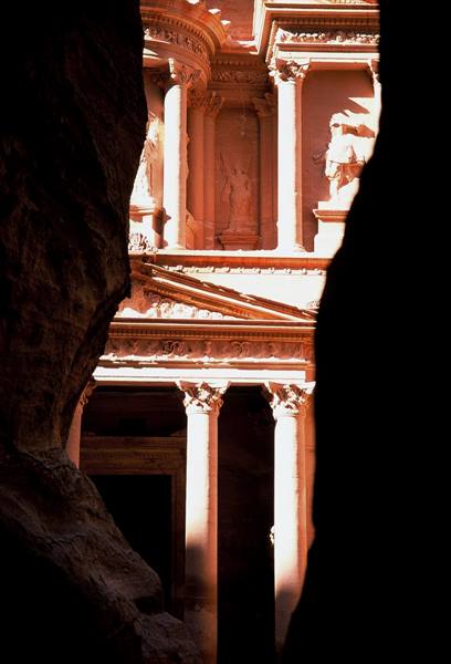 Al-Khazneh in Petra glimpsed through the Siq, golden light on sandstone