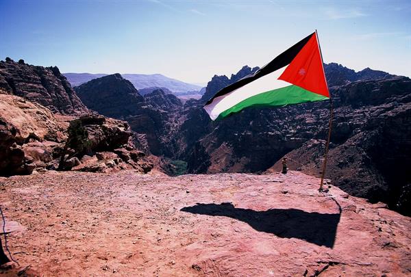 Jordanian flag waving over red rock above the mountains of Petra