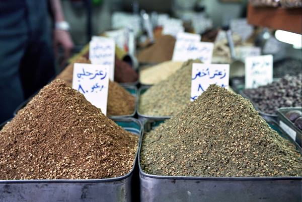 Piles of spices in metal bins at the souk, Arabic price signs
