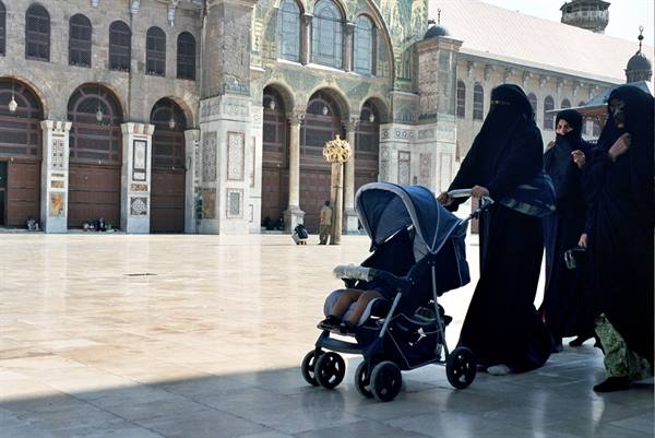 Veiled women push a stroller across the courtyard of the Umayyad Mosque