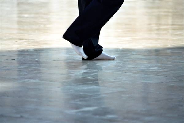 Feet in white socks walking across a polished marble floor