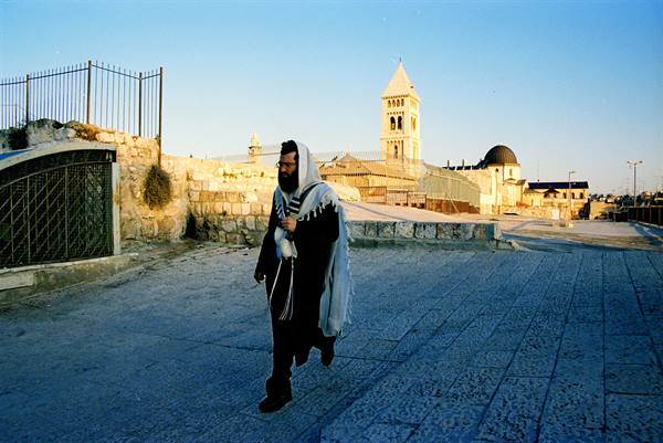 Orthodox Jewish man in tallit walks on ancient Jerusalem stone pavement
