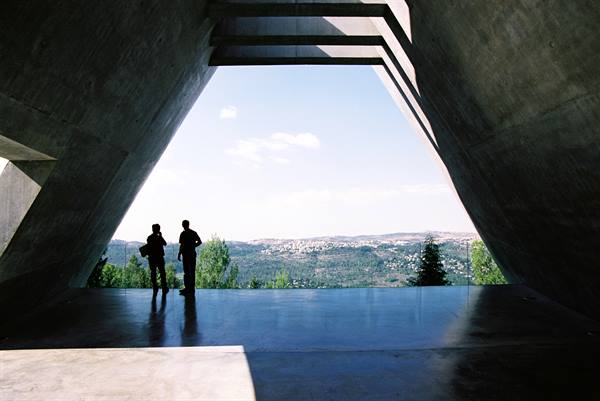 Two silhouetted visitors on Yad Vashem's concrete balcony overlooking the Jerusalem hills