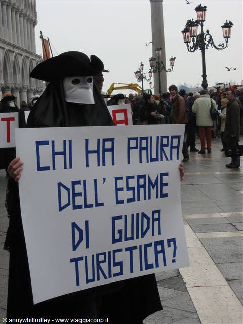 Protester in bauta mask holding sign in St Mark's Square, Venice