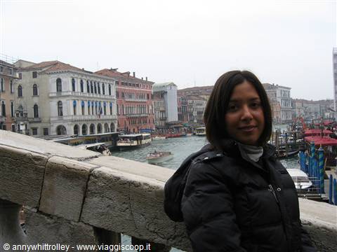 Woman on Rialto bridge, Grand Canal and Venetian palaces under grey sky